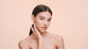 Young woman touching her slim, defined jawline after getting laser skin tightening treatment.