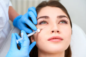 Close up of a beautiful young woman getting dermal filler injections for her under eye hollows
