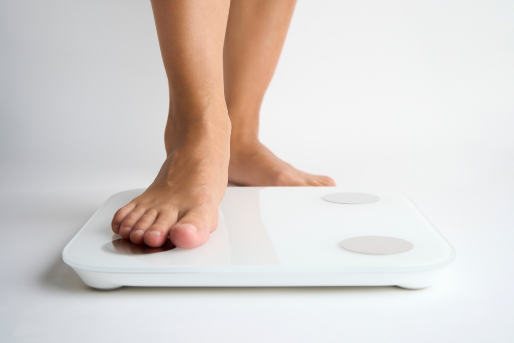 Close up of a woman's feet as she steps onto a scale to weigh herself while on Ozempic treatment