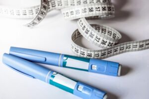 Semaglutide injections and a tape measure signifying it's medical weight loss treatment.