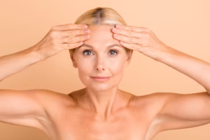 Older woman pulling the skin tight on her forehead, struggling with skin elasticity due to aging.