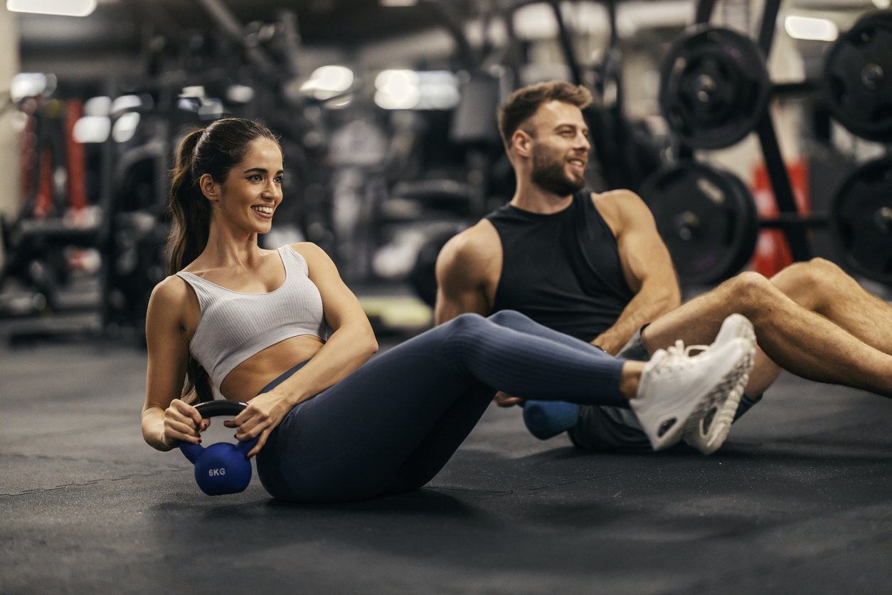 Two adults performing strength exercises with a kettlebell to help preserve lean muscle during GLP-1 weight loss.